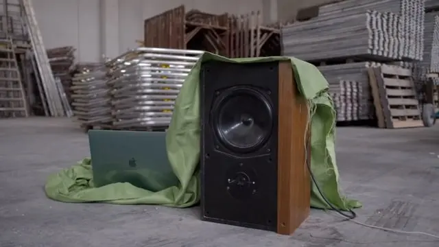 A speaker wrapped in green fabric in an industrial space