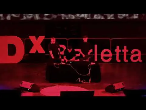 Performers silhouetted against a red TEDx Barletta stage