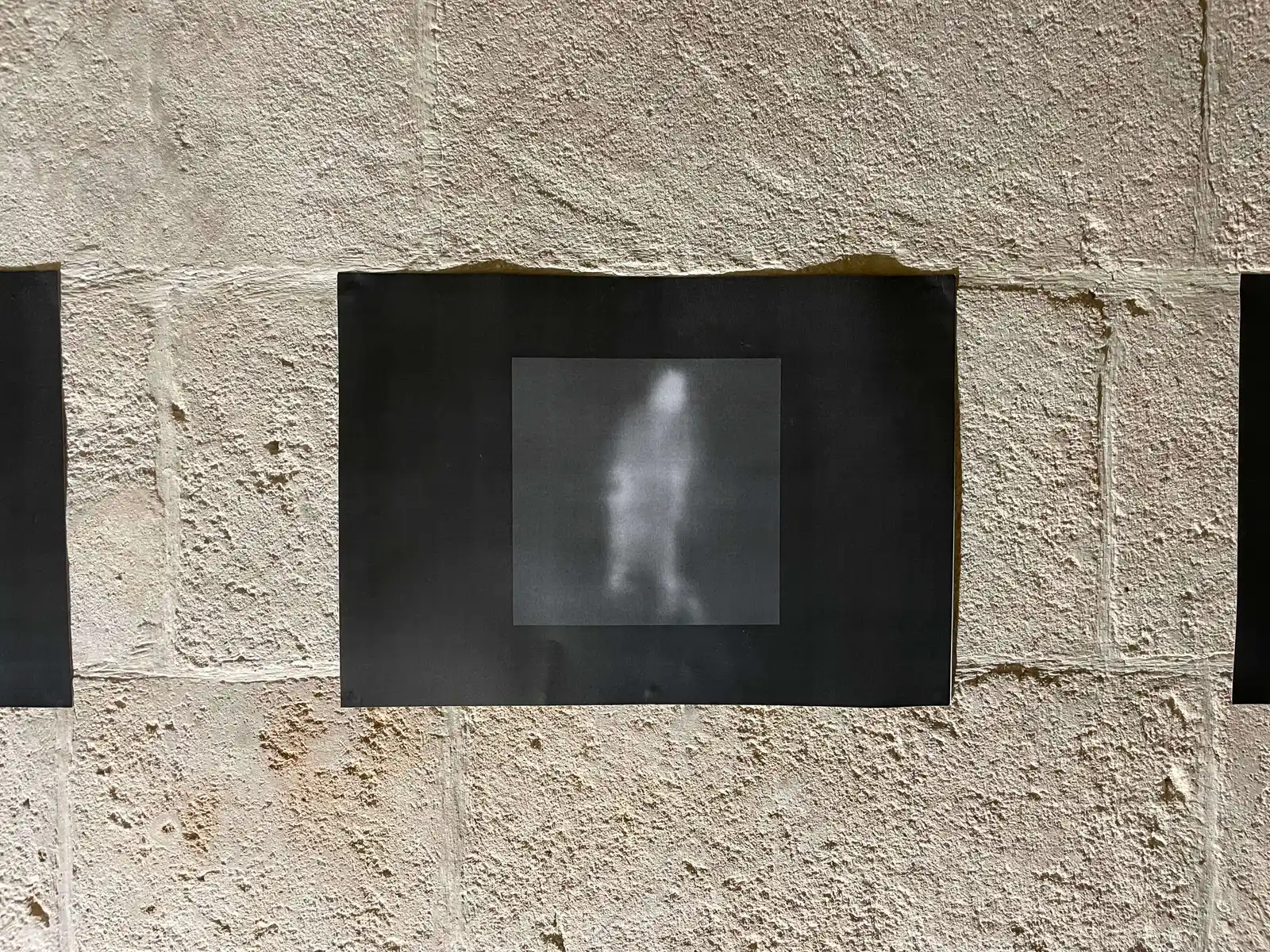 Small screen showing a blurred monochrome image on a textured wall