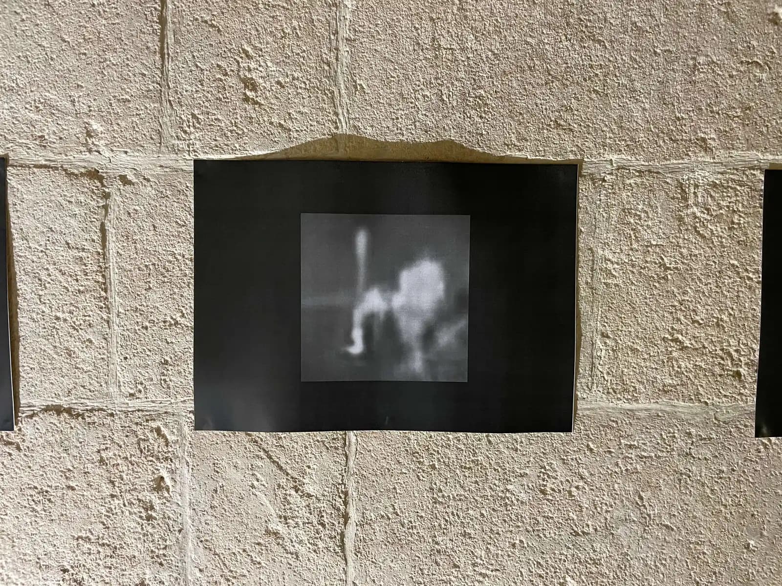 Small screen showing a blurred monochrome image on a textured wall